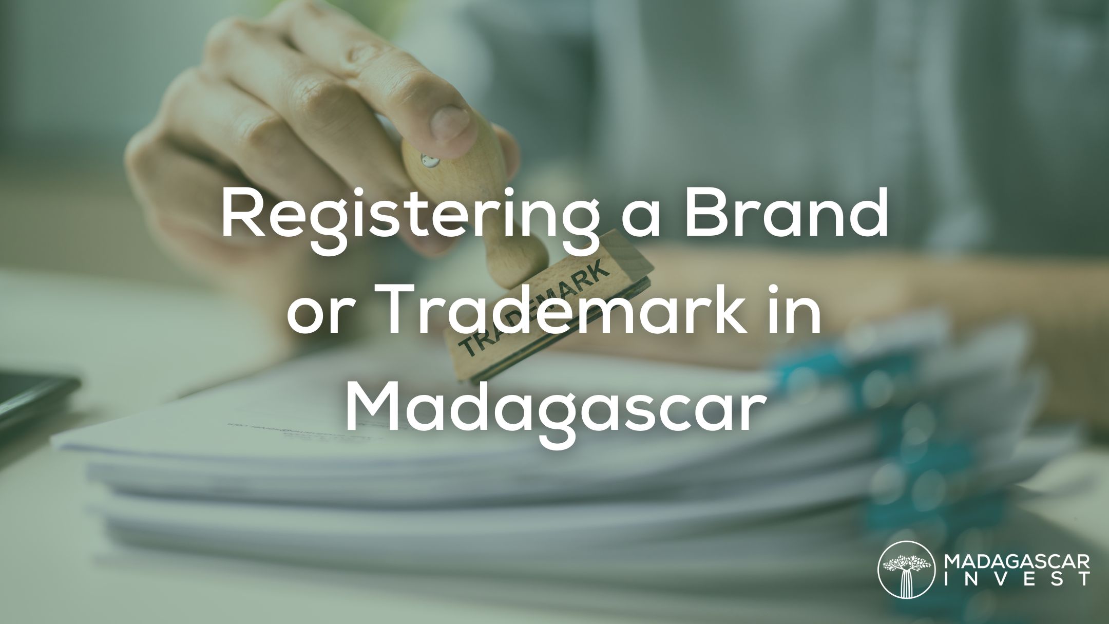 image showing a hand stamping a piece of paper with the words trademark, also featured is the madagascar invest logo